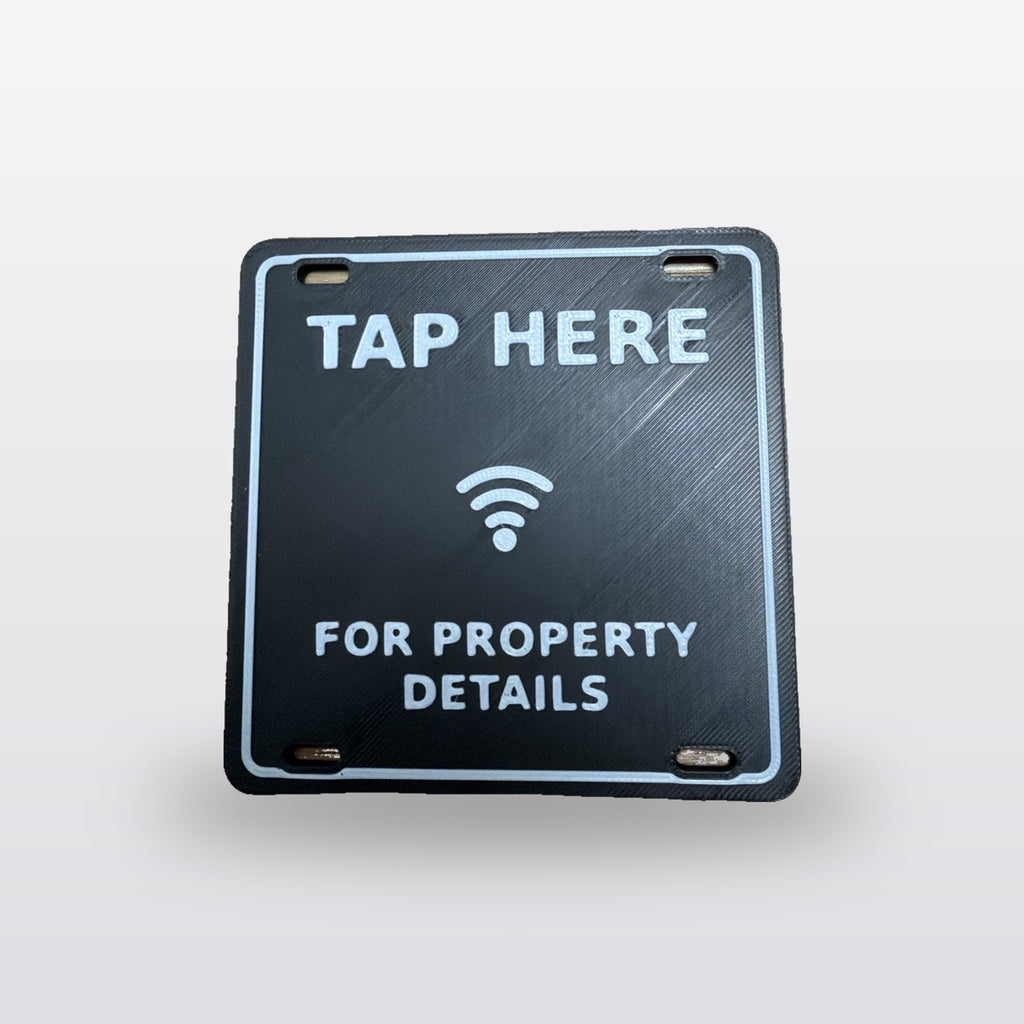 NFC A-Frame Sign Tag: real product photo, black tag with raised white TAP HERE, tap icon and FOR PROPERTY DETAILS, on a studio background