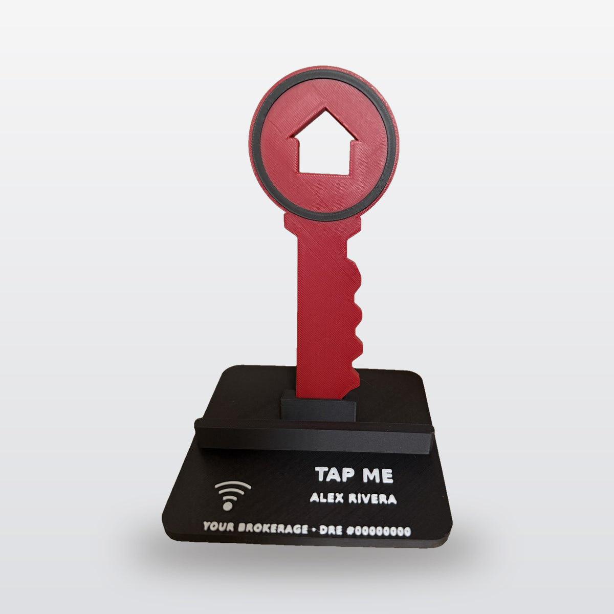 Key Phone Stand with NFC: real product photo (black base, white TAP ME text, red house key) on a clean studio background