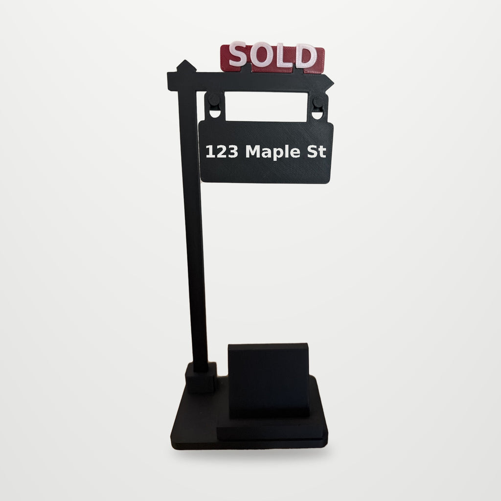 SOLD Sign Phone Stand with red SOLD rider and 123 Maple St sign, on a clean studio background (background added digitally)