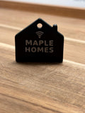 Real printed NFC house keychain, sample text MAPLE HOMES, on a wood table