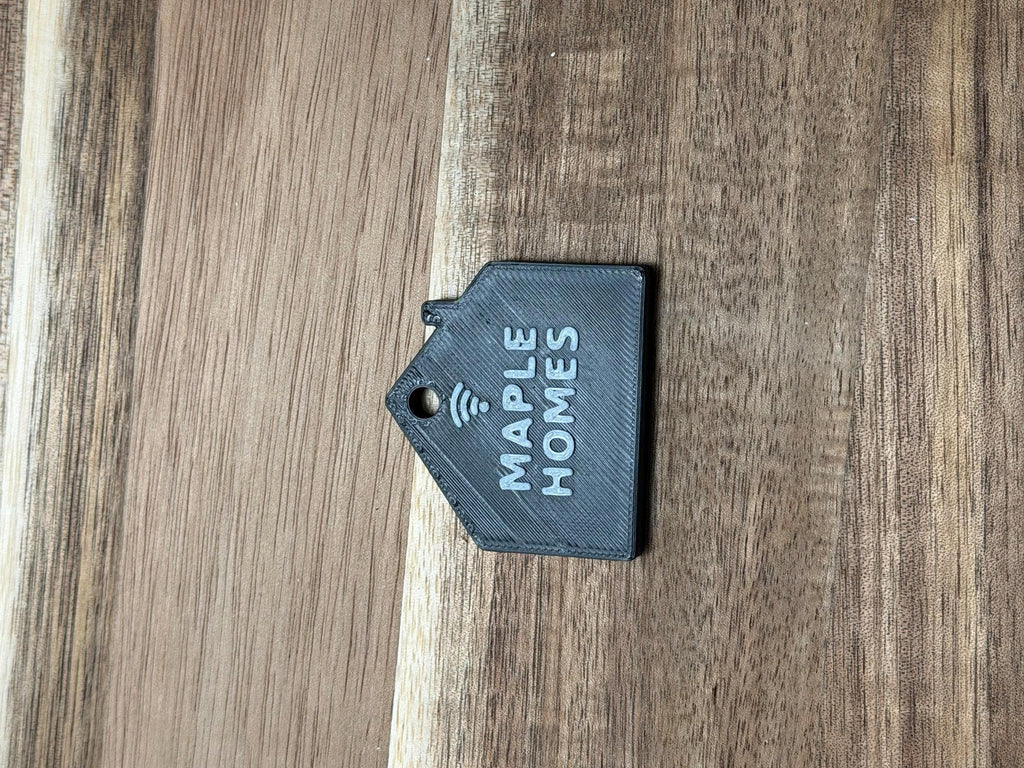 Real printed NFC house keychain lying flat, showing print layer lines